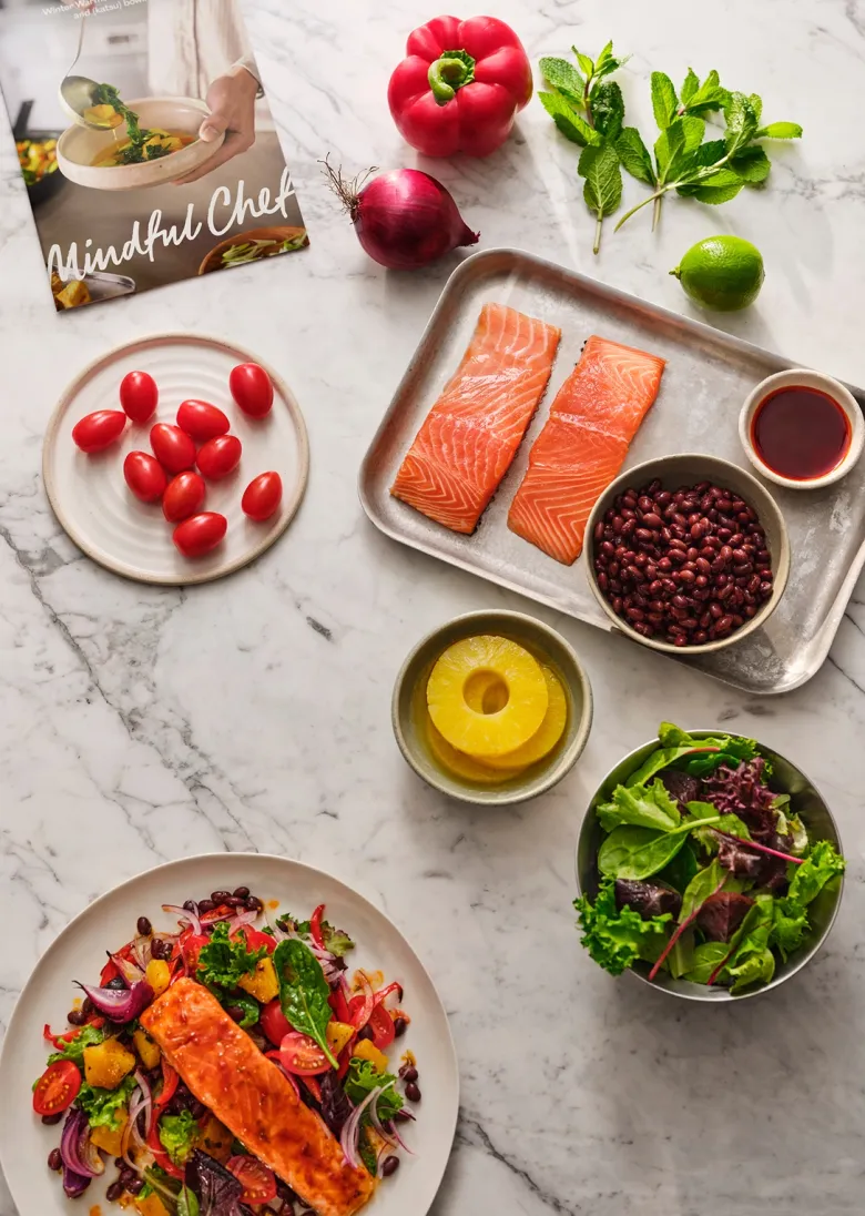 An open Mindful Chef healthy recipe box showcasing fresh, pre-portioned ingredients and recipe cards for healthy meals delivered to your door.