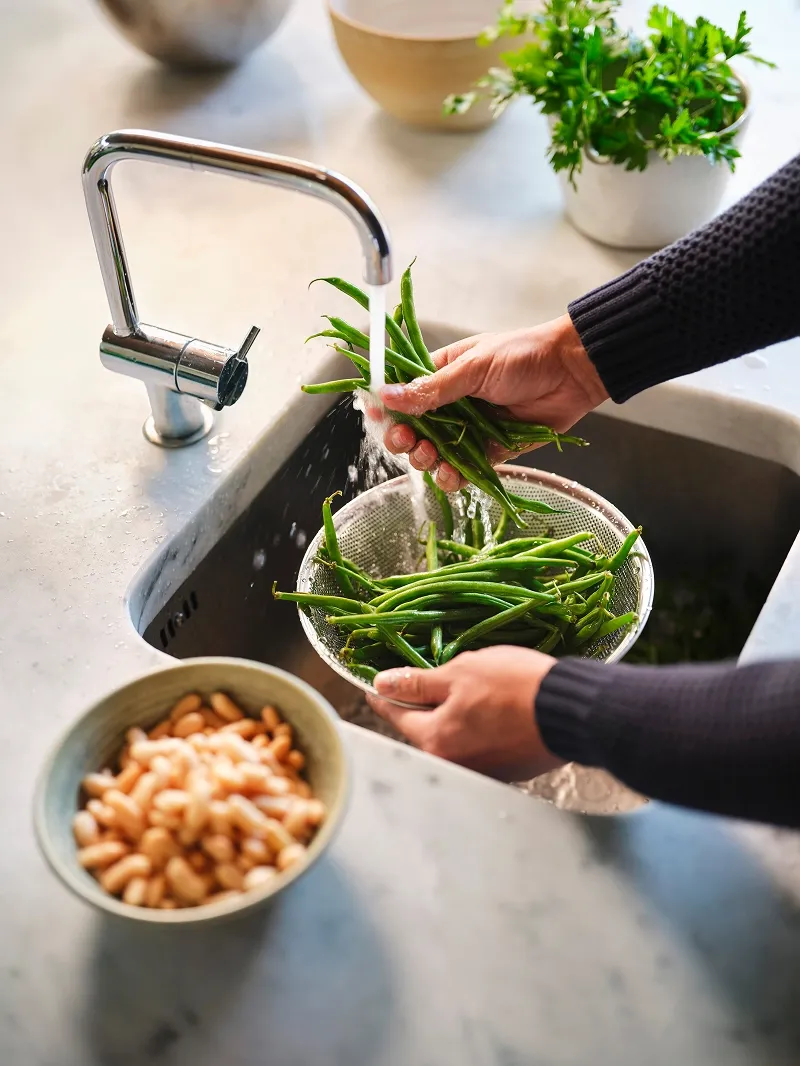 Washing fresh green beans in the sink.