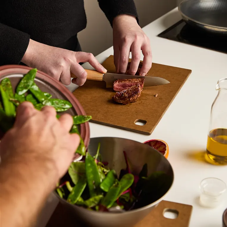 Seared steak being sliced beside a bowl of mangetout salad